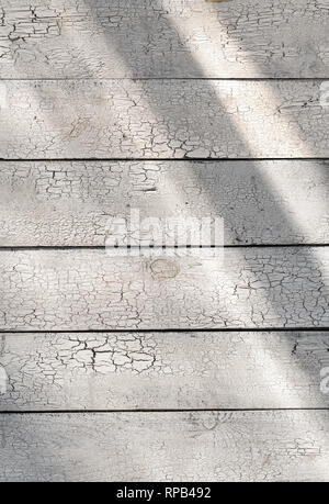 Vernice incrinata sul bianco sullo sfondo di legno malandata tavole rustico con la luce solare Foto Stock