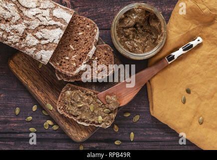 Pane di segale fatto in casa con semi di zucca fatti in casa spalmati su un panino di legno Foto Stock