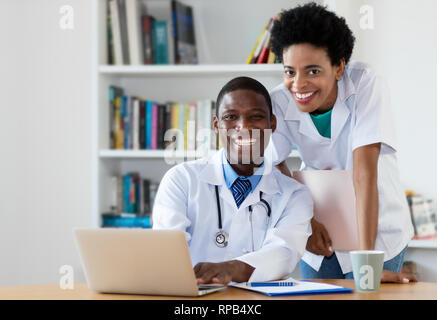 African American medico con un infermiere guardando la fotocamera all'ospedale Foto Stock
