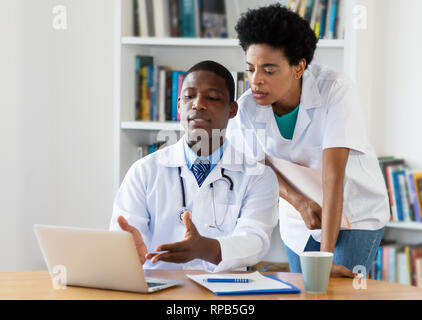 African American medico a parlare con un infermiere circa il paziente in ospedale Foto Stock