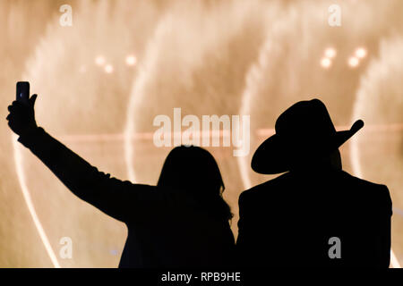 LAS VEGAS, NEVADA, STATI UNITI D'AMERICA - Febbraio 2019: uomo che indossa il cappello da cowboy e la donna prendendo un selfie stagliano fontane dell'Hotel Bellagio in La Foto Stock