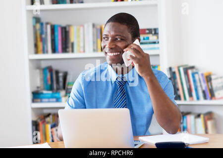 African American imprenditore con cravatta al telefono cellulare in ufficio Foto Stock