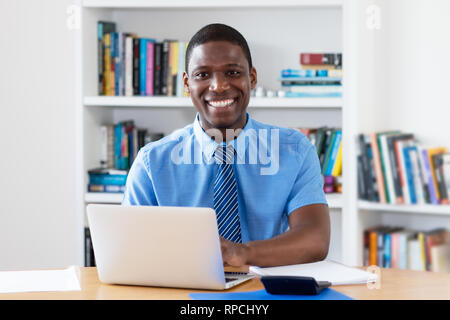 Ridendo African American imprenditore con cravatta al computer in ufficio Foto Stock