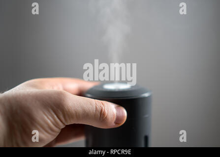 Mano d'uomo girando su elettrico umidificatore d'aria. Foto Stock