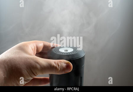 Mano d'uomo girando su elettrico umidificatore d'aria. Foto Stock