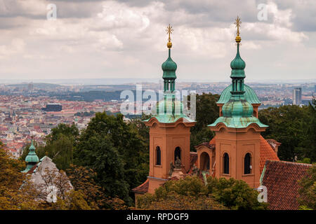 Le torri della Cattedrale di Saint Lawrence (Praga) con la città di Praga in background su un nuvoloso giorno d'autunno. Paesaggio urbano in Europa. Foto Stock