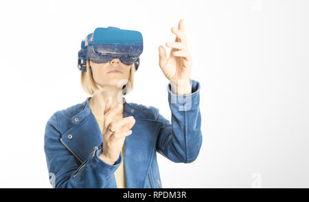 Una giovane donna indossa occhiali per realtà virtuale e toccante aria durante l'esperienza di VR isolato su bianco Foto Stock