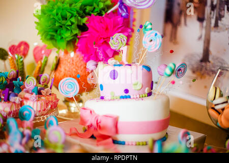 Primo compleanno di torta rosa con lecca-lecca e una candela per la piccola  bambina e decorazioni per il partito Foto stock - Alamy