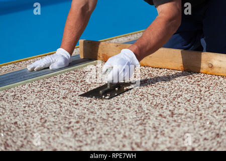 L'operatore colloca un tappeto di pietra con resina. (Shallow DOF Foto  stock - Alamy