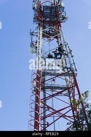 Due saldatrici lavorando su alta torre di telecomunicazione. Foto Stock