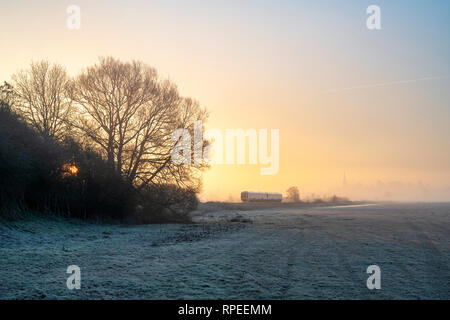 In treno la nebbia a sunrise nel gelo invernale. Kings Sutton, Nr Banbury, Northamptonshire, Inghilterra Foto Stock