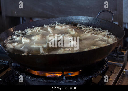 Pepite di pollo con panatura che vengono fritti in padella su un fornello a gas. Foto Stock