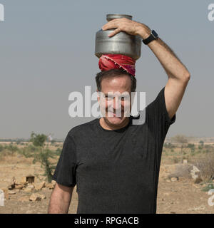 Felice l'uomo che trasportano l'acqua vaso sul suo capo Jaisalmer, Rajasthan, India Foto Stock