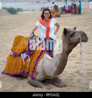 Felice donna in piedi vicino a cammello nel deserto, Kanoi, Jaisalmer, Rajasthan, India Foto Stock