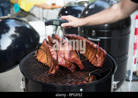 Primo piano di un uomo misurando la temperatura della carne sul barbecue. Foto Stock