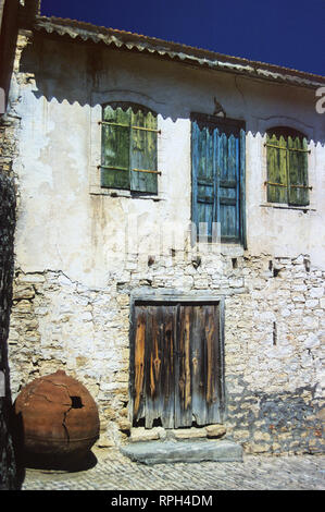 Pittoresca vecchia casa con porta weatherbeaten e persiane e pithoi enorme: villaggio di Lofou, Cipro Foto Stock