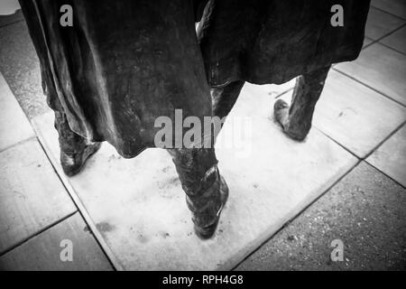 Un drammatico in bianco e nero vista della metà inferiore di due statue in bronzo di Doc Holiday e Wyatt Earp indossare i loro cowboy duster cappotti a sud Foto Stock