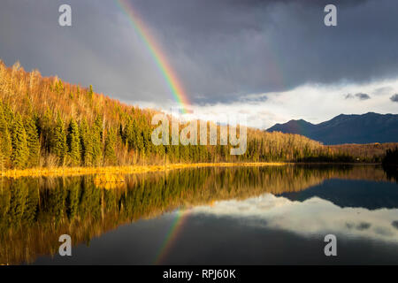 Rainbow riflessa nel lago tranquillo dopo una breve doccia a pioggia. Foto Stock