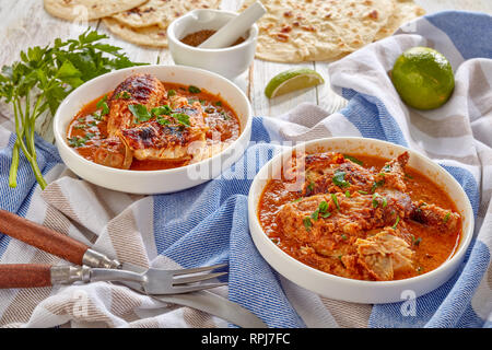 Stufato di pollo in crema piccante salsa di cocco, kuku paka, servita su una bianca bocce con chapati flatbread su un vecchio tavolo di legno, vista da sopra, chiudi Foto Stock