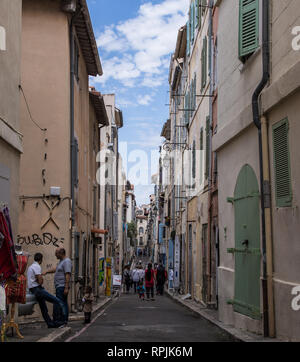 Le persone camminare lungo uno dei tanti vicoli stretti della storica città vecchia di Marsiglia, Francia, su una giornata di primavera. Foto Stock