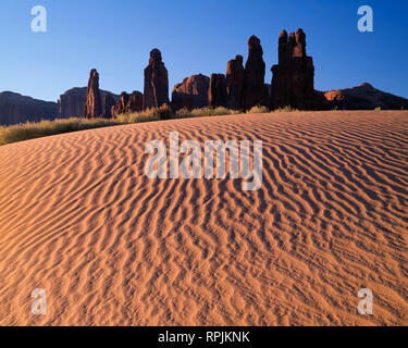 Stati Uniti d'America, Arizona, il parco tribale Navajo, Sunrise definisce la texture di dune di sabbia con torri di roccia chiamato Yei-Bi-Chei aumento nella distanza. Foto Stock