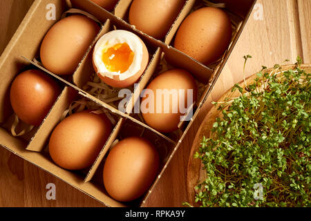 Organici di uova di pollo in scatola di carta sulle uova con vani e piastra di germogli di crescione Foto Stock