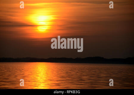 Tramonto sul mare con un cielo nebbioso e colori caldi. Foto Stock