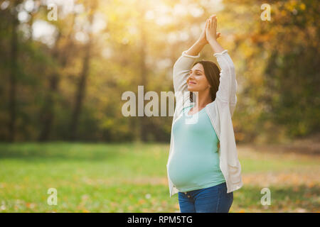 Donna incinta relax nel parco. Ella è la meditazione. Foto Stock