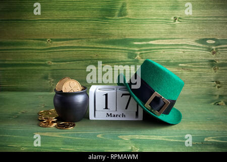 Block Bianco calendario per il giorno di San Patrizio, 17 marzo con Leprechaun hat e pot di oro su legno verde dello sfondo. Foto Stock