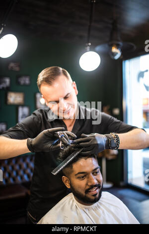 Giovane ragazzo bello taglia i capelli, uomo taglia i capelli in Barberia Foto Stock