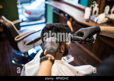 attraente barbiere che fa taglio di capelli di bell'uomo in barbiere,  accessori per capelli Foto stock - Alamy