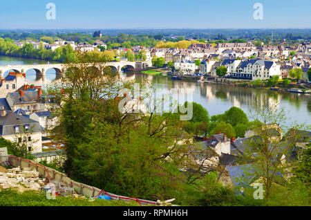 Vista mozzafiato sul sorprendente piccola città di Saumur, Francia. Molti di bianco e grigio case nei pressi di un fiume Loira, ponte arcuato, un sacco di alberi verdi e tetti Foto Stock