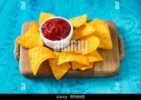 Tortilla chips e dip di pomodoro su una superficie di legno Foto Stock