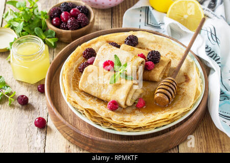 Frittelle di sana prima colazione. Pila di casalinga frittelle sottili o crepes su un tavolo rustico, servito con miele e frutti di bosco freschi. Foto Stock