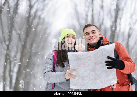 Migliori amici cercando qualcosa in inverno boschi innevati, essi azienda mappa Foto Stock