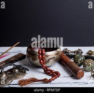 Il rame Singing Bowl, grani di preghiera, preghiera tamburo, le sfere di pietra e le altre religiose tibetane oggetti, spazio di copia Foto Stock