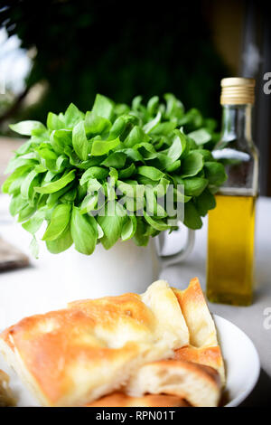La DOP Fresca basilico genovese, una bottiglia di olio extra vergine di oliva e e la tradizionale focaccia, tre elementi essenziali della dieta genovese Foto Stock