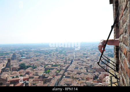 Dettaglio di un uomo del braccio appoggiato su una delle finestre sulla sommità della torre degli Asinelli a Bologna, Italia Foto Stock