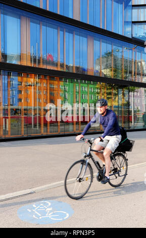 Uomo in sella ad una bicicletta di fronte ad uno dei recentemente terminato edifici del campus di Erste, Vienna, Austria Foto Stock