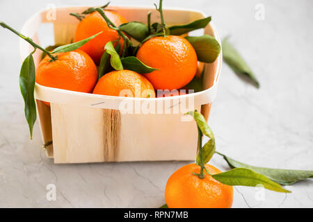Clementine fresche di agrumi in un cestello, organico sano clementine con foglie Foto Stock