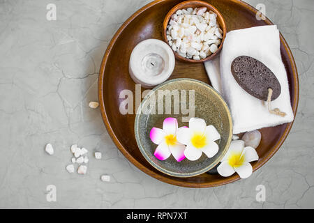 I prodotti Spa nel vassoio in legno, vista dall'alto di spa elementi con fiori di frangipani, candela, sale da bagno, asciugamano e ponce pietra, spa ancora impostazione di vita Foto Stock