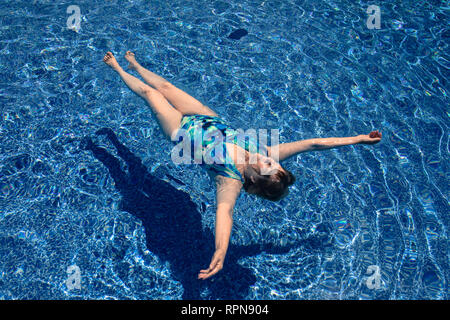 Senior donna galleggianti in piscina. Foto Stock