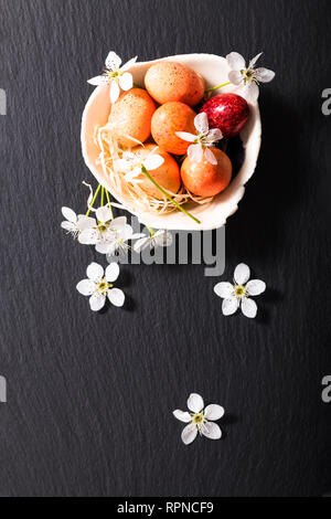Vacanze concetto alimentare caramelle colorate e uova di pasqua di cioccolato nero sulla piastra di ardesia con spazio di copia Foto Stock