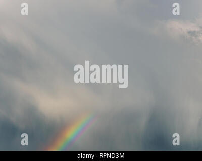 Rainbow sulla drammatica del cielo e i raggi del sole Foto Stock