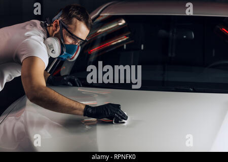 Attraente operosi guy strofinando la polvere della vettura. close up foto. spazio copia Foto Stock