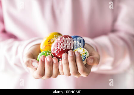 Close-up multicolore di uova di pasqua in ragazze mani. Foto Stock
