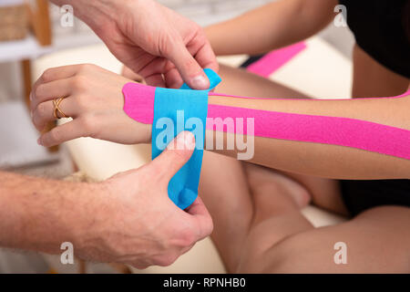 Close-up di Uomo Blu applicazione Physio Tape sulla donna di polso Foto Stock