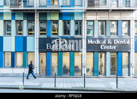 Città di Bruxelles / Belgio - 02 15 2019: pedonale passando dalla facciata dell'ufficio Eurocare con rettangolare forme blu e vetro Foto Stock