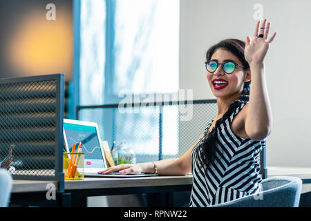 Carino longhaired ragazza seduta al suo posto di lavoro Foto Stock