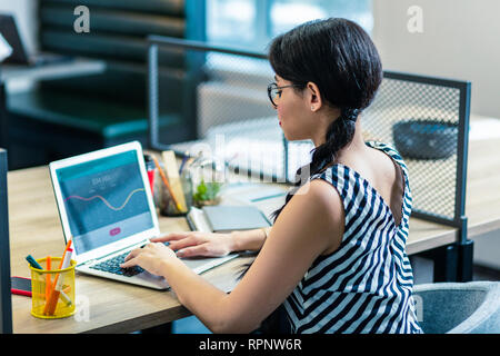 Concentrato longhaired ragazza seduta al suo posto di lavoro Foto Stock